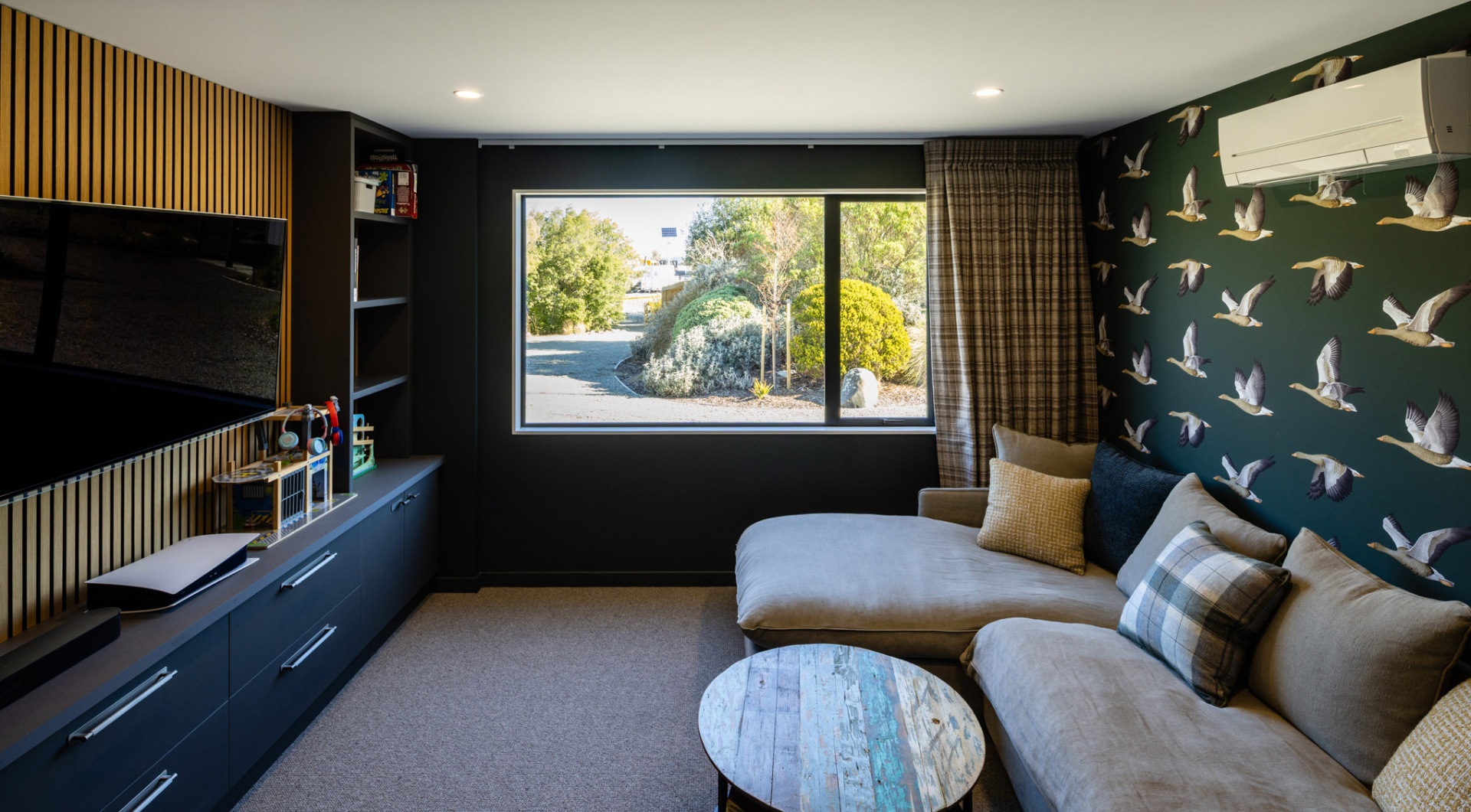 Cosy media room with feature wallpaper and lounger at Whakahā